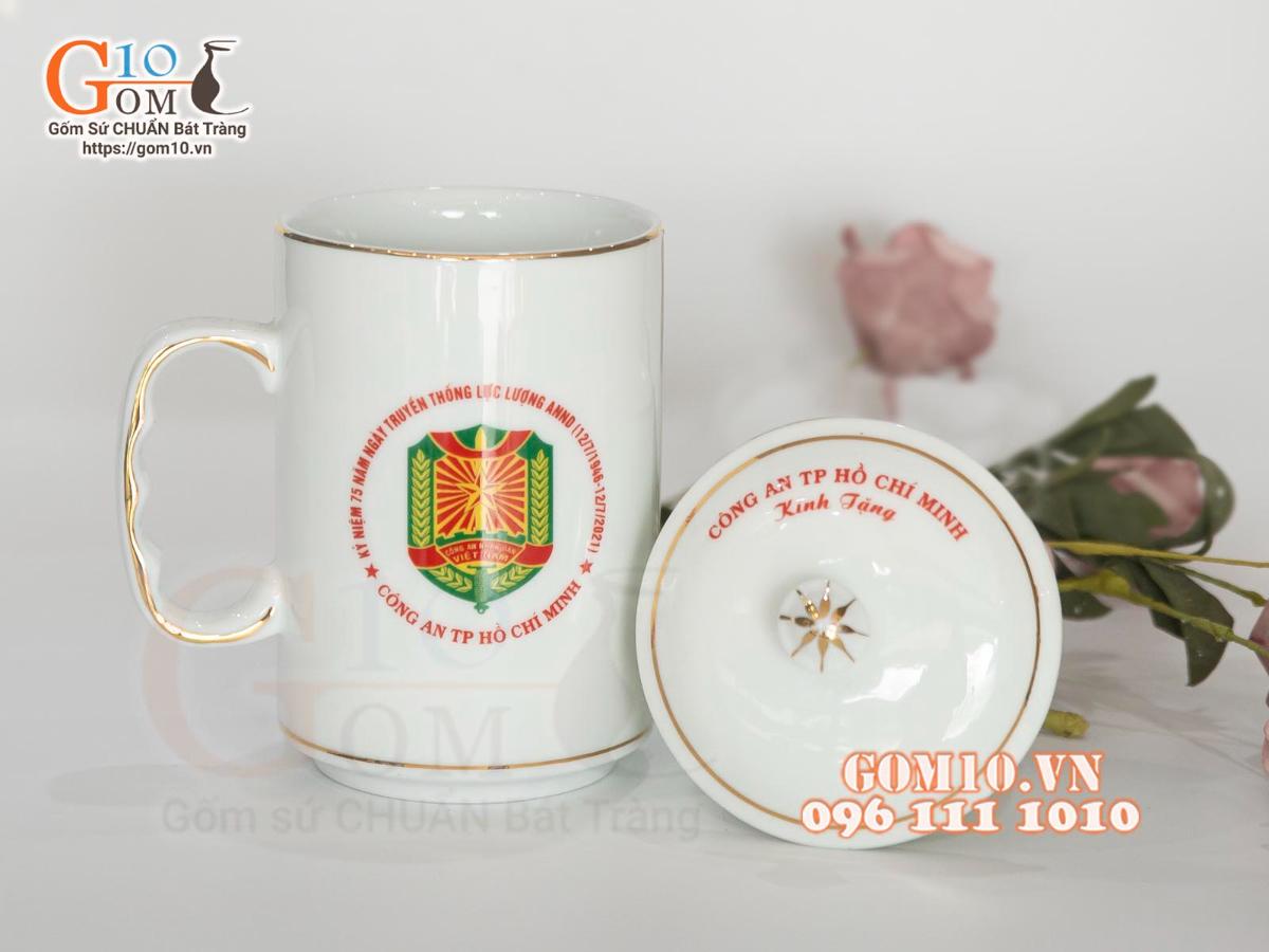 Cốc sứ dáng cao quai nắm men trắng kẻ chỉ vàng kim in logo CA TP HCM, 500ml Cốc sứ dáng cao quai nắm men trắng kẻ chỉ vàng kim in logo CA TP HCM, 500ml