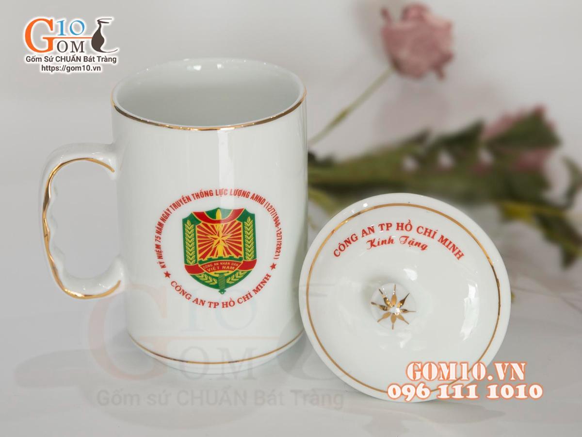 Cốc sứ dáng cao quai nắm men trắng kẻ chỉ vàng kim in logo CA TP HCM, 500ml Cốc sứ dáng cao quai nắm men trắng kẻ chỉ vàng kim in logo CA TP HCM, 500ml