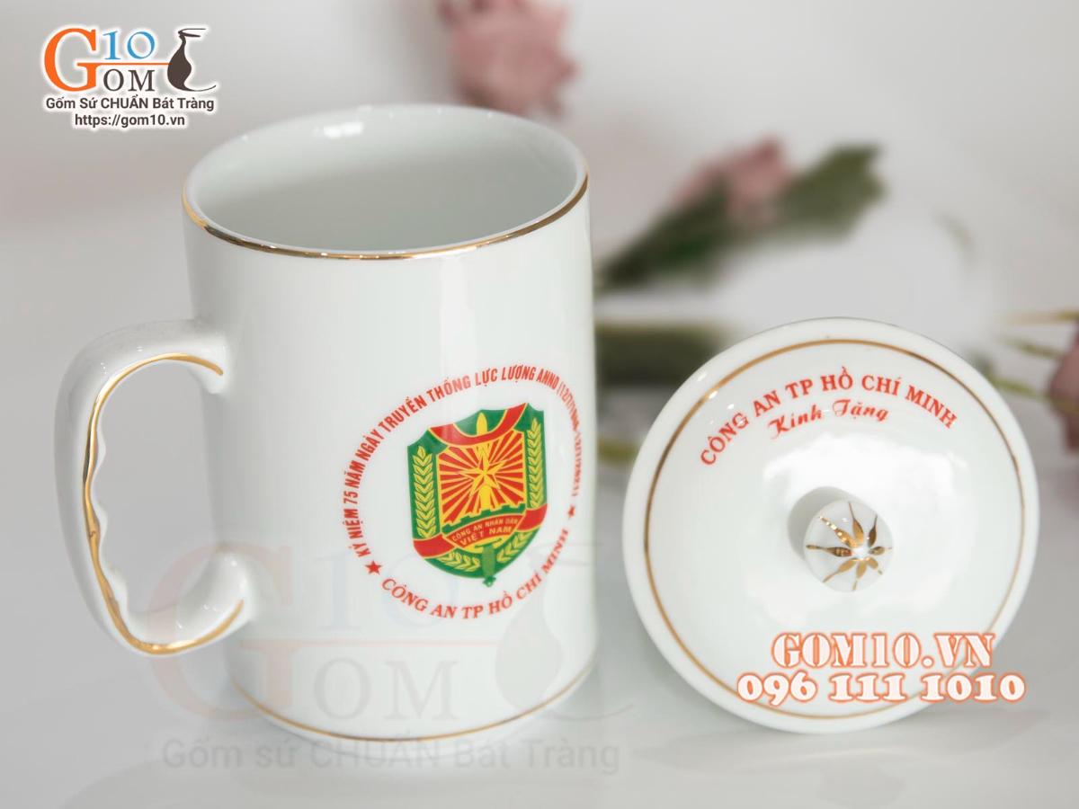 Cốc sứ dáng cao quai nắm men trắng kẻ chỉ vàng kim in logo CA TP HCM, 500ml Cốc sứ dáng cao quai nắm men trắng kẻ chỉ vàng kim in logo CA TP HCM, 500ml